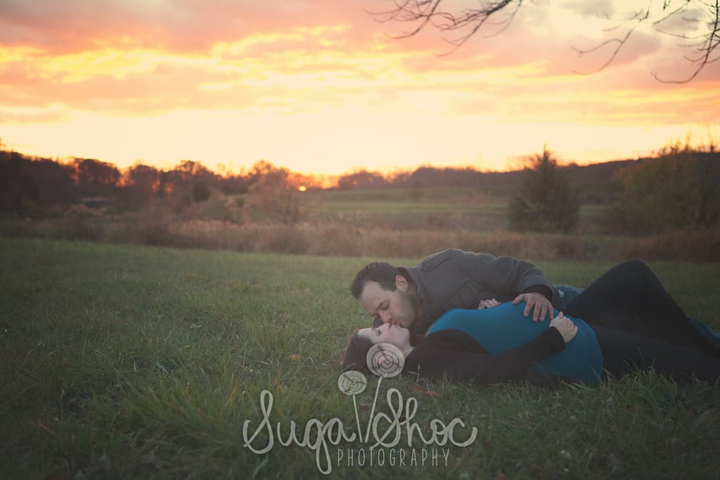 SugaShoc_Photography_Maternity_Photographer_Bucks County_Doylestown_PA_mother_posed_at_sunset_outdoors_laying_down_kissing_husband