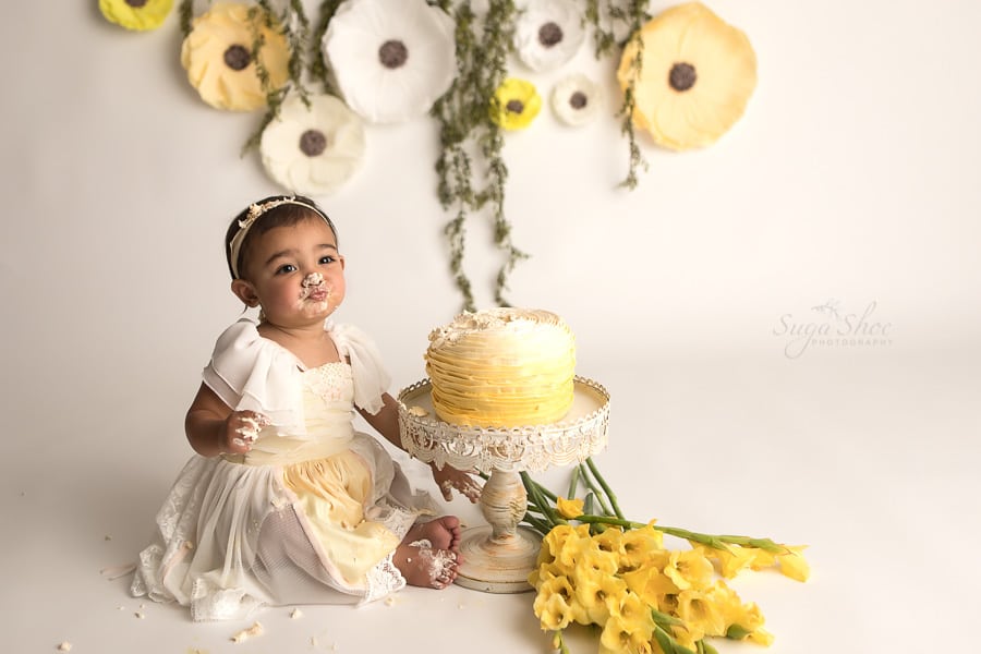 SugaShoc_Photography_Cake_Smash_Photographer_Bucks_County_PA_Doylestown_PA_Cream_and_yellow_theme_making_kissy_lips_cake_on_feet_yellow_flowers
