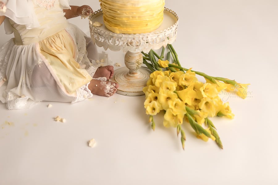 SugaShoc_Photography_Cake_Smash_Photographer_Bucks_County_PA_Doylestown_PA_Cream_and_yellow_theme_cake_on_feet_yellow_flowers