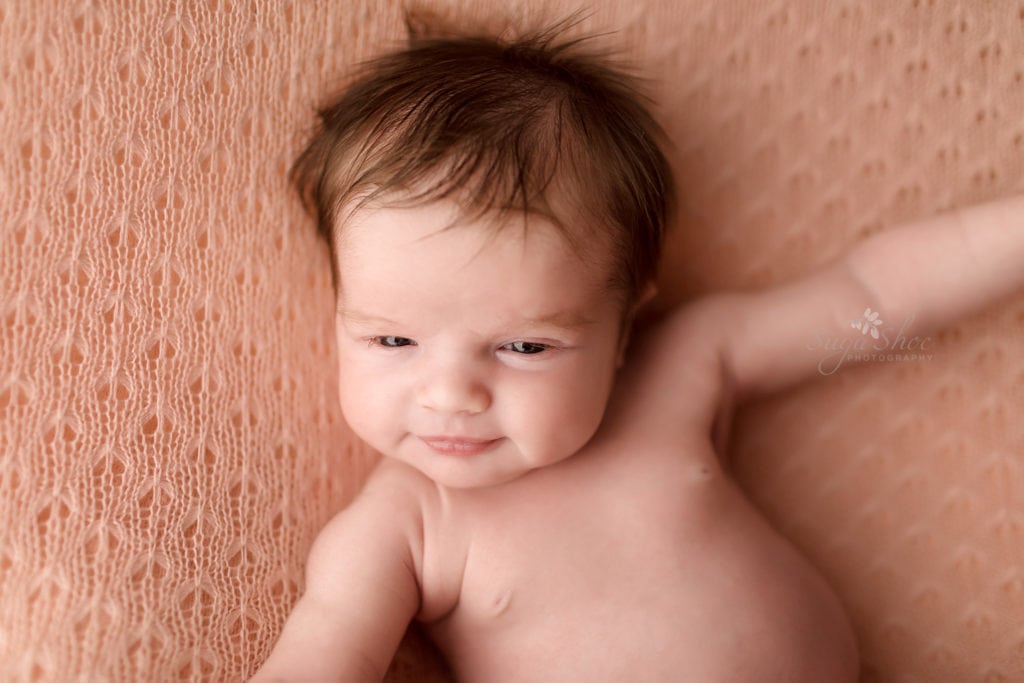 SugaShoc Photography Newborn Photographer Bucks County PA Doylestown PA Keeping Babies Asleep Baby girl awake laying pink blanket on back