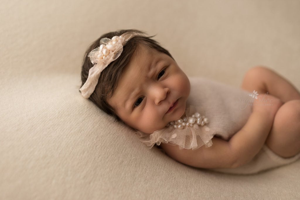 SugaShoc Photography Newborn Photographer Bucks County PA Doylestown PA Keeping Babies Asleep Baby girl awake laying cream blanket wearing cream and pearl onesie and matching headband