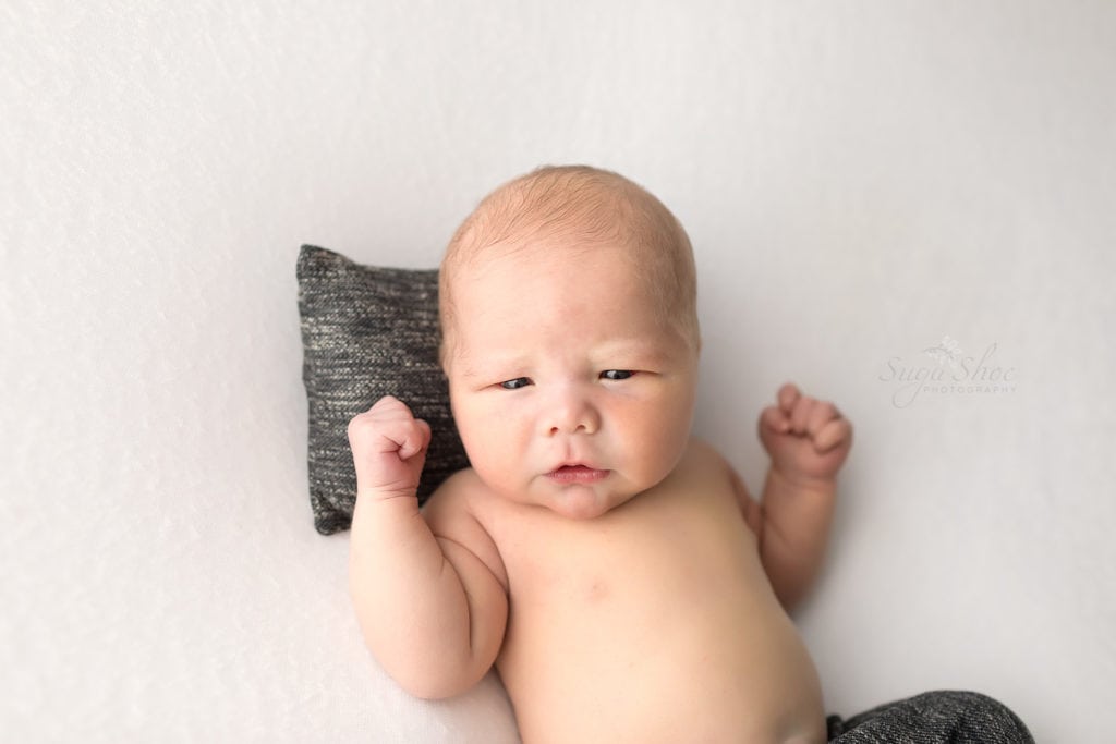 SugaShoc Photography Newborn Photographer Bucks County PA Doylestown PA Baby boy laying on small gray pillow with matching pants looking at camera