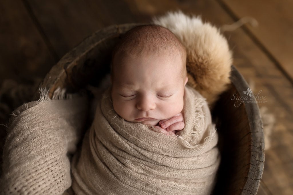 SugaShoc Photography Newborn Photographer Bucks County PA Doylestown PA Baby Hunter Newborn Session sleeping wooden bucket wrapped in tan wrap with fun throw