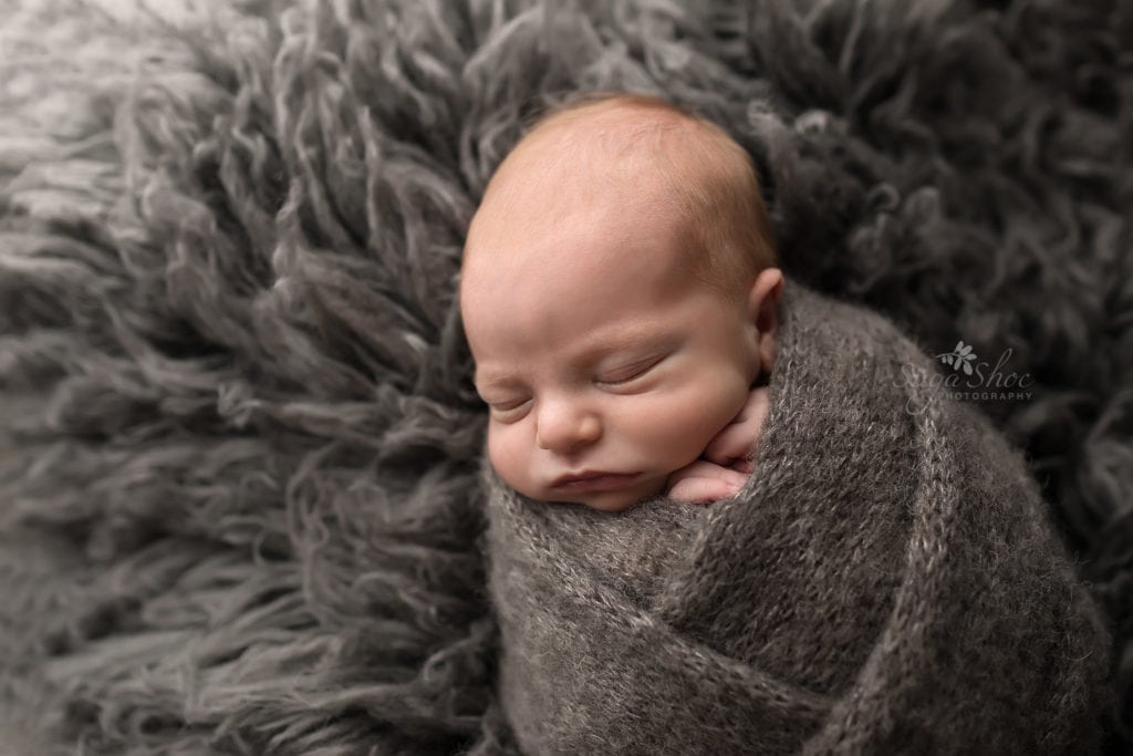 SugaShoc Photography Newborn Photographer Bucks County PA Doylestown PA Baby Hunter Newborn Session sleeping wrapped in gray knit blanket on gray flokati rug