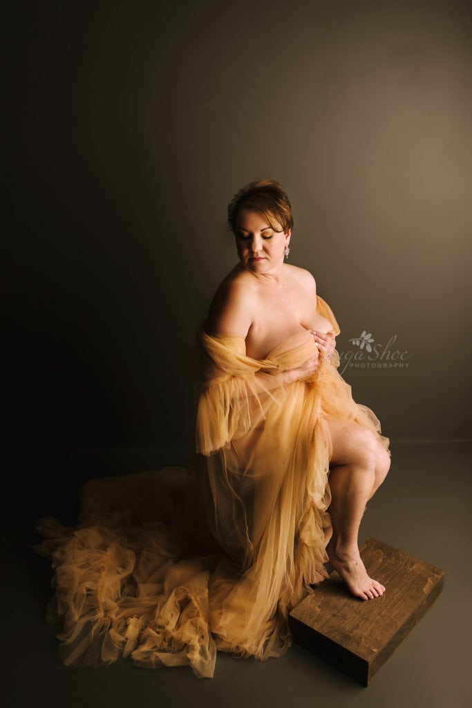 SugaShoc Photography Doylestown Boudoir Photographer PA Floral Boudoir Session boudoir pose sitting on stool draped in gold tulle looking down over shoulder