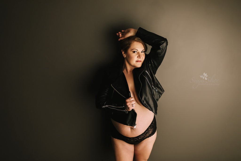 SugaShoc Photography Doylestown Boudoir Photographer PA Floral Boudoir Session boudoir pose standing against dark wall wearing open leather jacket and lace panty