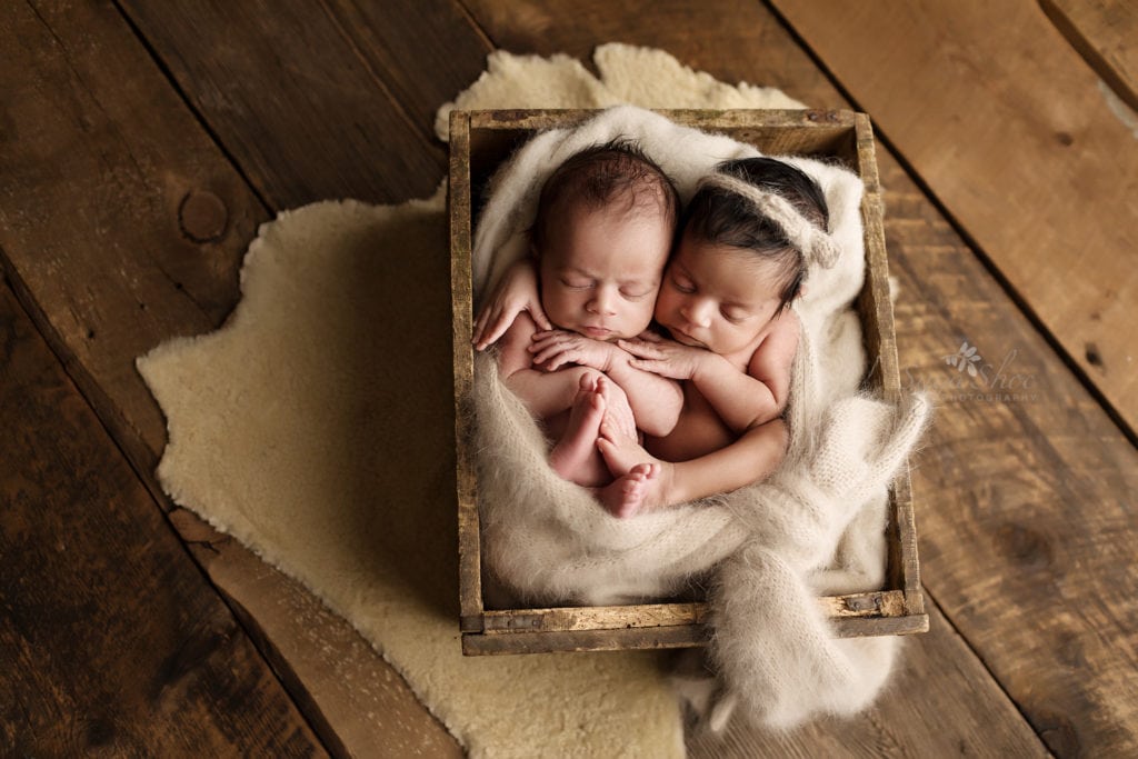 SugaShoc Photography Newborn Photography Bucks County PA Doylestown PA Newborn Twin Photographer baby twins sleeping in a crate on wooden floor with oatmeal color wrap