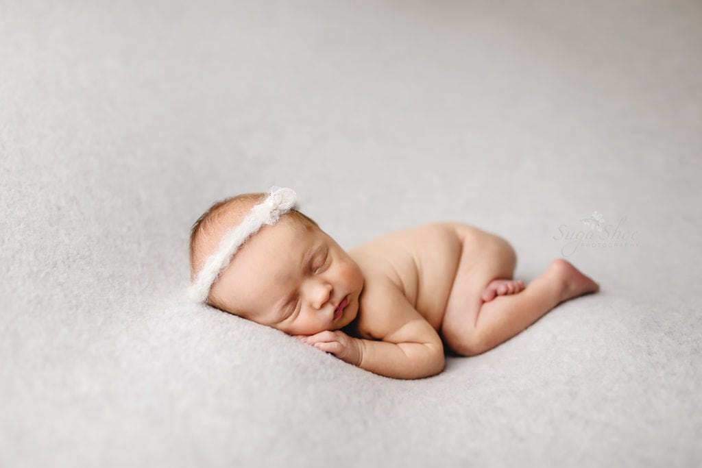 SugaShoc Photography Newborn Photography Bucks County PA Doylestown PA Newborn Photographer Rainbow Newborn Session baby sleeping on white blanket wearing white headband