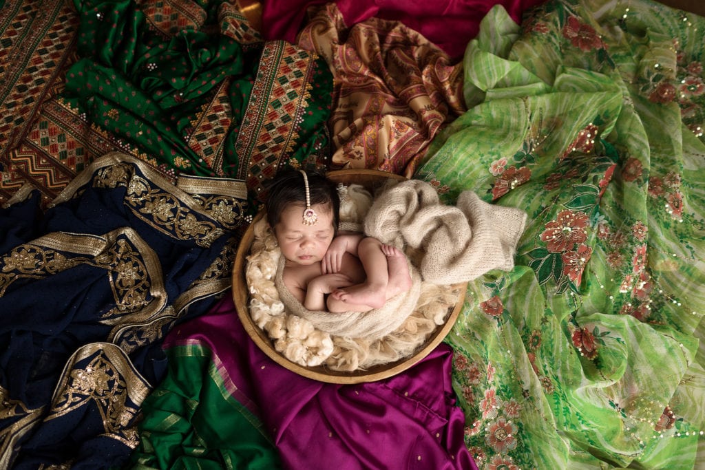 SugaShoc Photography Newborn Photography Bucks County PA Doylestown PA Newborn Photographer Sari Newborn Session baby sleeping in wooden bowl surrounded by Indian saris