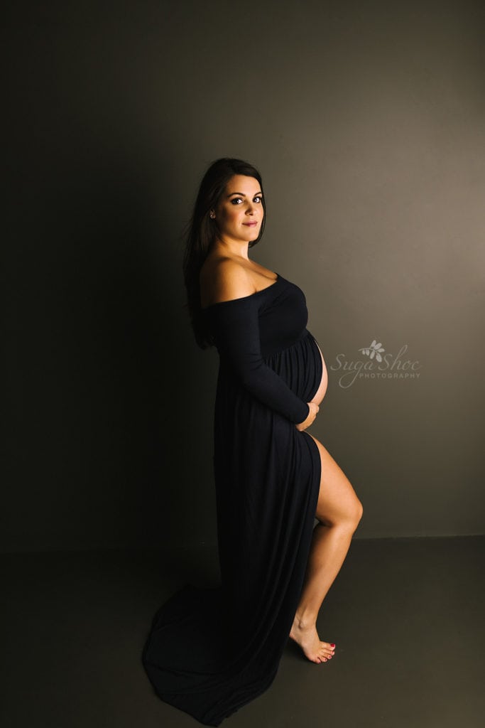 SugaShoc Photography Twin Maternity Session Bucks County PA Doylestown PA Maternity Photographer Maternity pose standing against dark wall wearing navy off the shoulder maternity dress