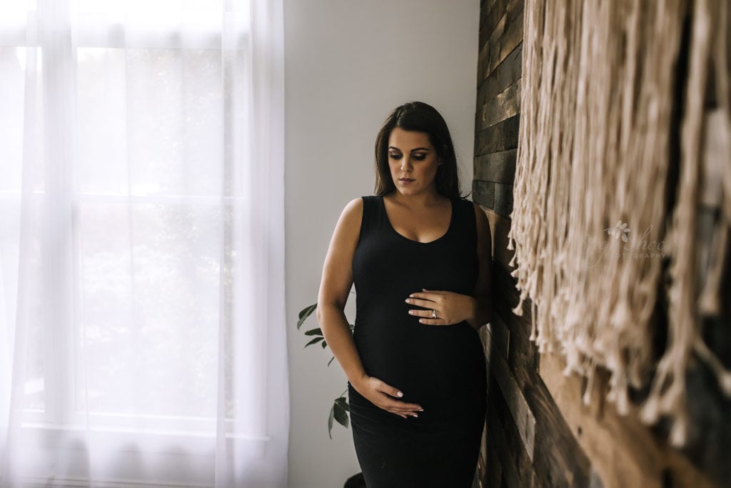 SugaShoc Photography Twin Maternity Session Bucks County PA Doylestown PA Maternity Photographer Maternity pose standing against wooden wall wearing black maternity dress holding belly looking down