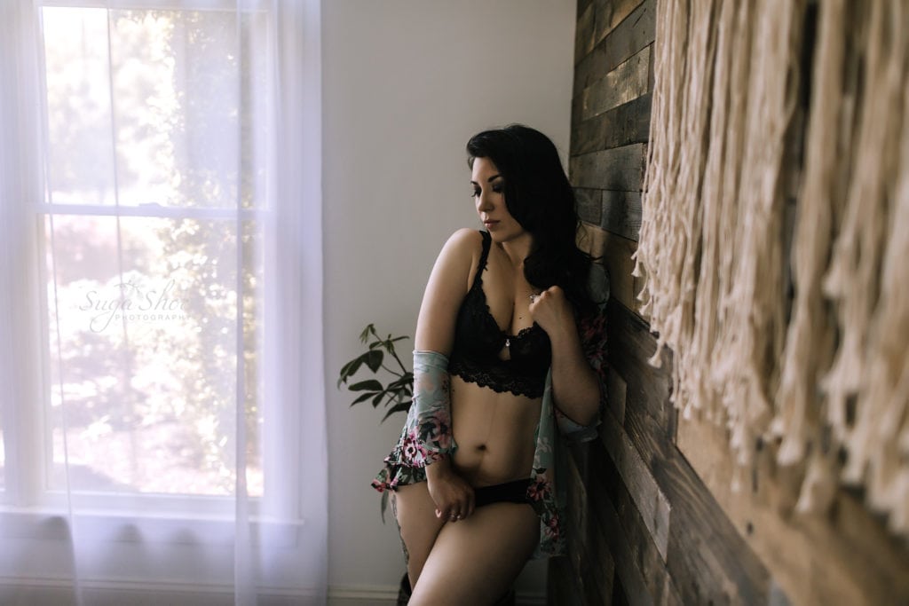 SugaShoc Photography Birthday Boudoir pose standing against wall wearing black lace bra and panty with open floral robe