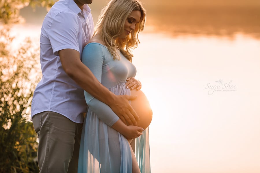 Sugashoc Photography Doylestown Maternity Photographer couple by lake with sunset on belly