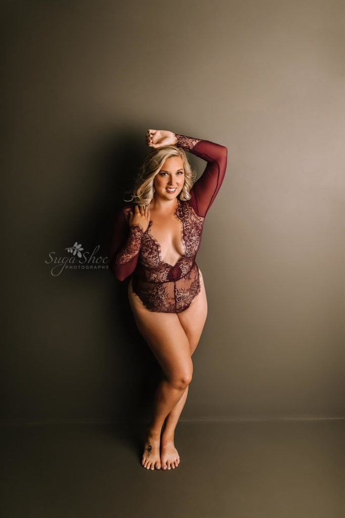 Anniversary Boudoir Sugashoc Photography standing against wall wearing dark red lace teddy smiling