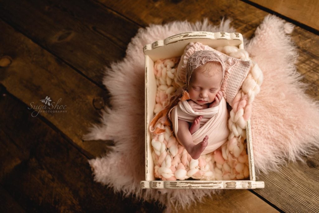 Sugashoc Photography Montgomery County Newborn Photographer newborn girl sleeping in little bed with pink blankets
