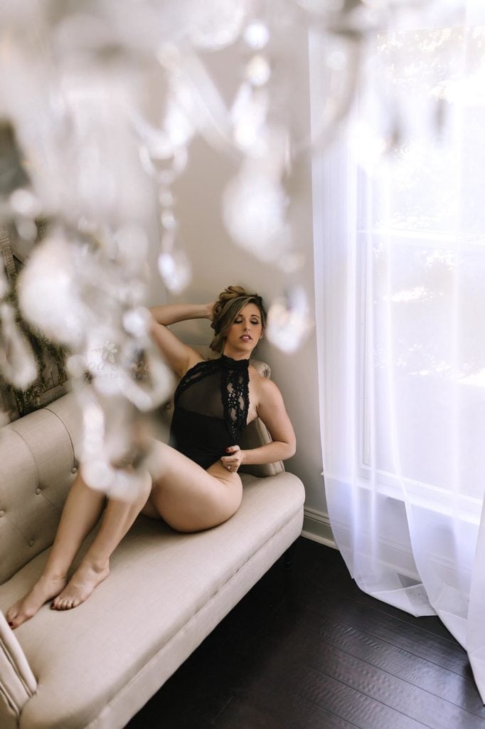 Sugashoc Photography Fiance Boudoir sitting on caise wearing black teddy looking through chandelier