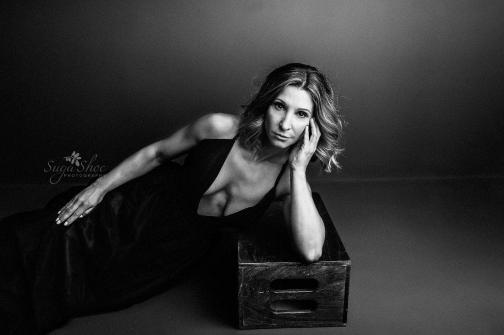 Philly Boudoir Photographer SugaShoc Photography low-cut black gown leaning on crate black-and-white