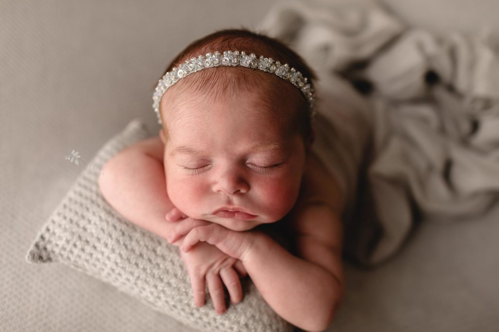 Sugashoc Photography Newborn photography baby girl sleeping on gray blanket wrapped in cream with sparkly headband