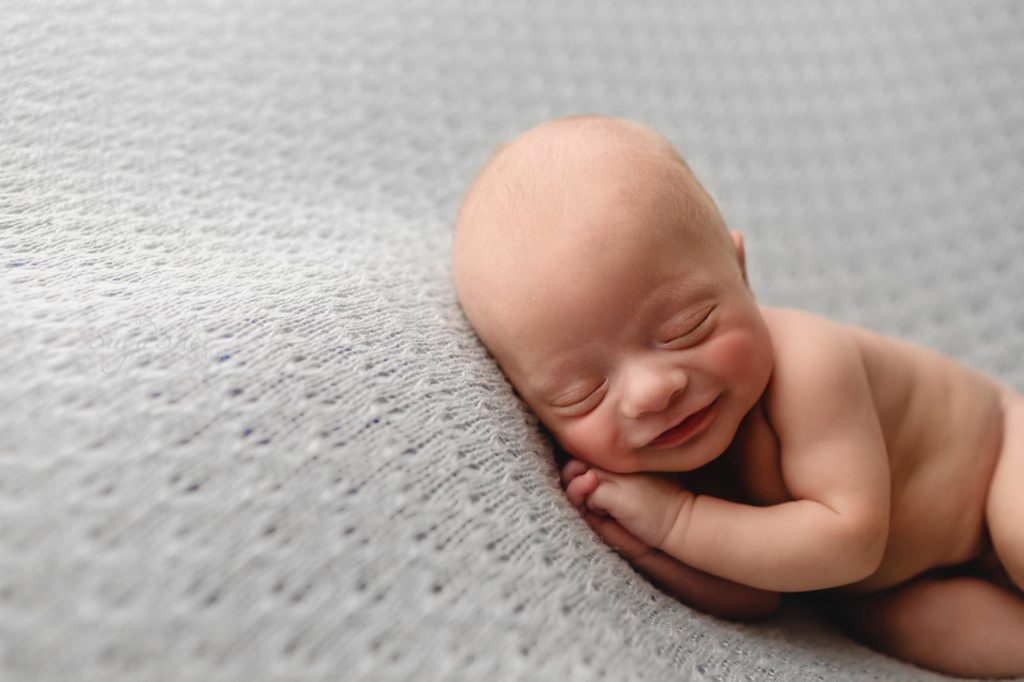 SugaShoc Photography Neutral Newborn Photo Session, smiling baby on gray blanket