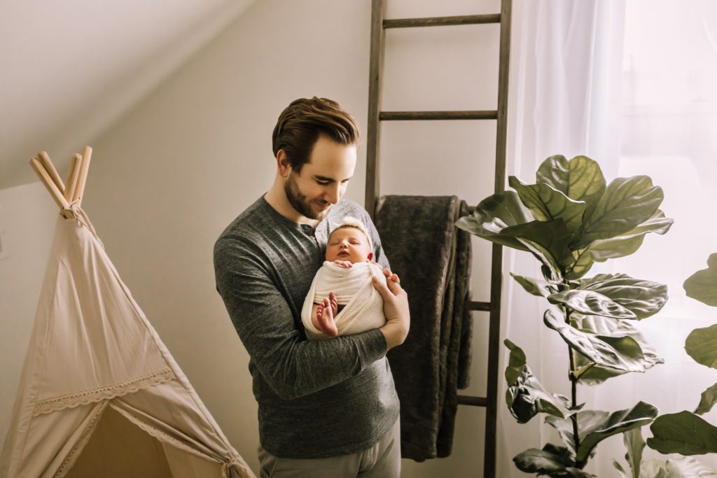 lifestyle newborn photography pennsylvania, dad holding swaddled infant near window
