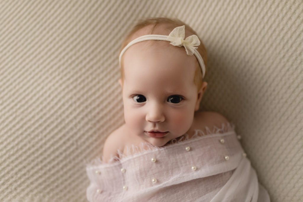 baby photographer near me pennsylvania, wakeful baby covered with sheer pink blanket lined with pearls