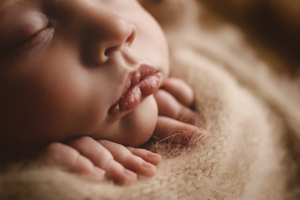 close-up of baby's face with fingers tucked under chin