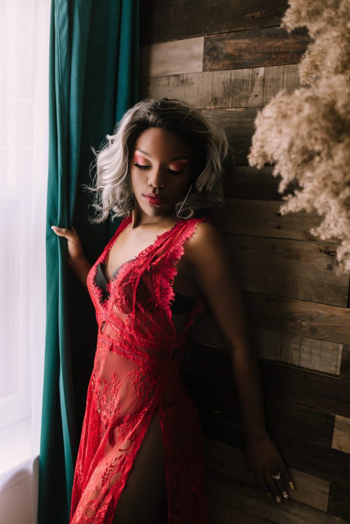 beauty photography, woman in sheer red lace dress posing by window