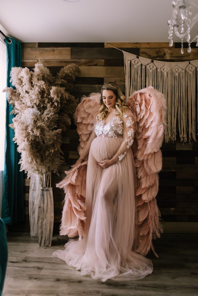 maternity pictures near me bucks county pa, standing woman in flowing maternity gown with pink "Victoria's Secret" angel wings