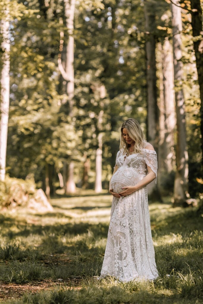 maternity photographs, mother in white maternity gown standing in sunshine