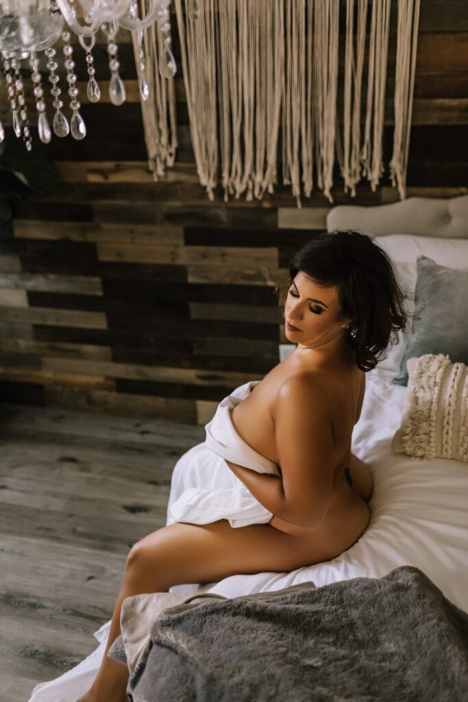 Pennsylvania boudoir photographer, nude woman sitting on bed holding sheet