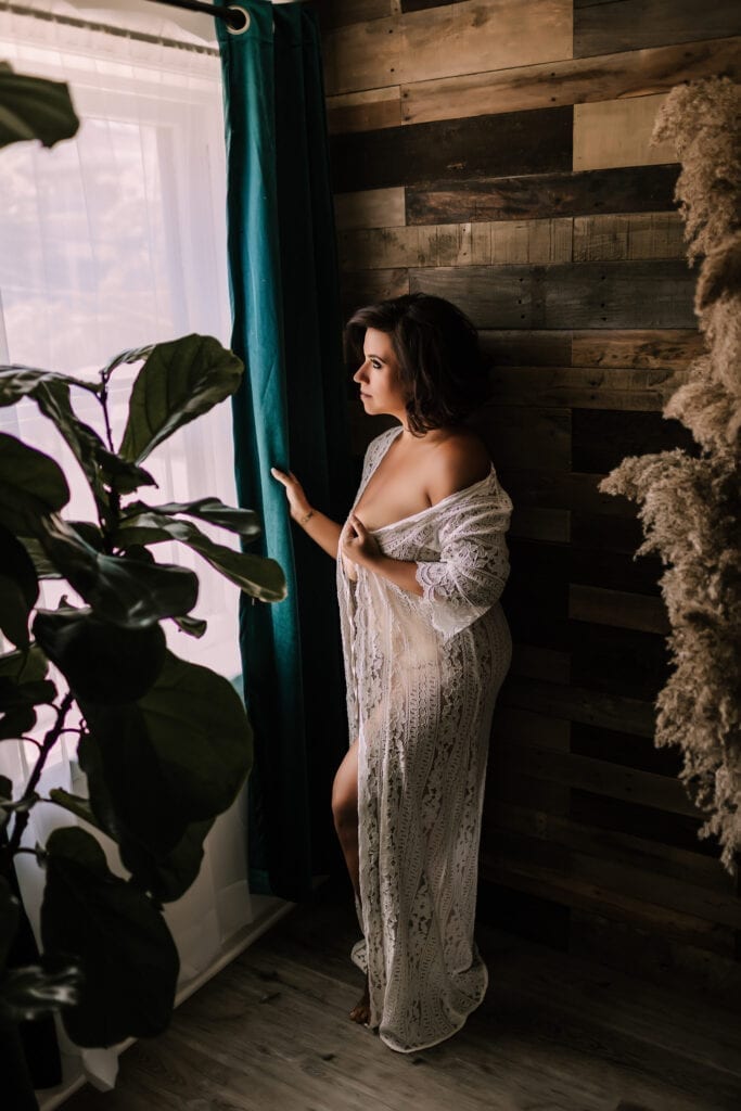 boudoir photography, woman in sheer white gown standing by window