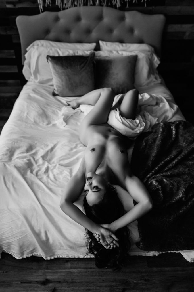 black and white photo of nude woman reclining on bed