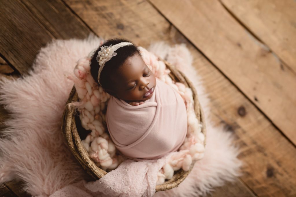 Newborn baby girl in studio photo shoot with mom and dad using subtle feminine touches.
