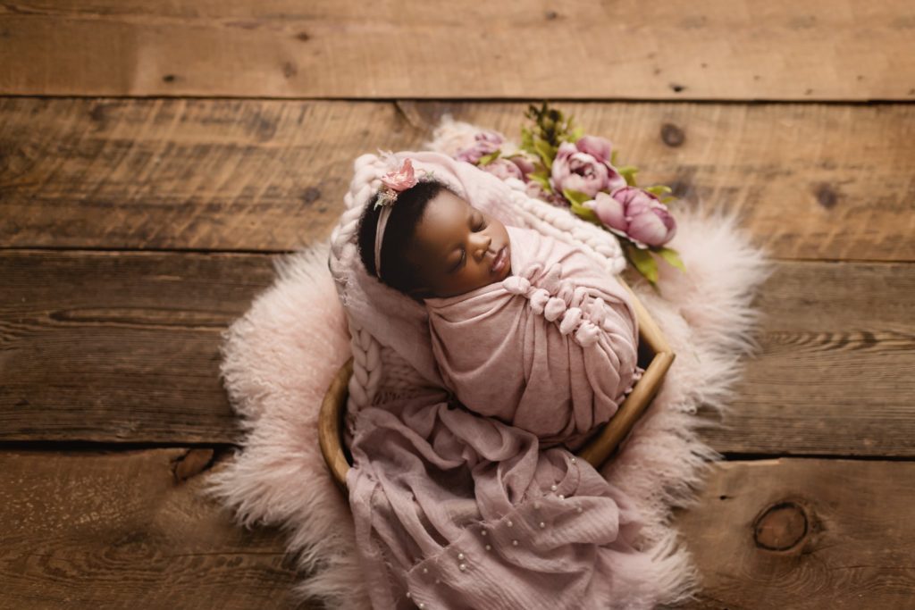 Newborn baby girl in studio photo shoot using subtle feminine touches.