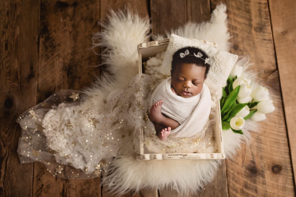 Newborn baby girl in studio photo shoot with mom and dad using subtle feminine touches.