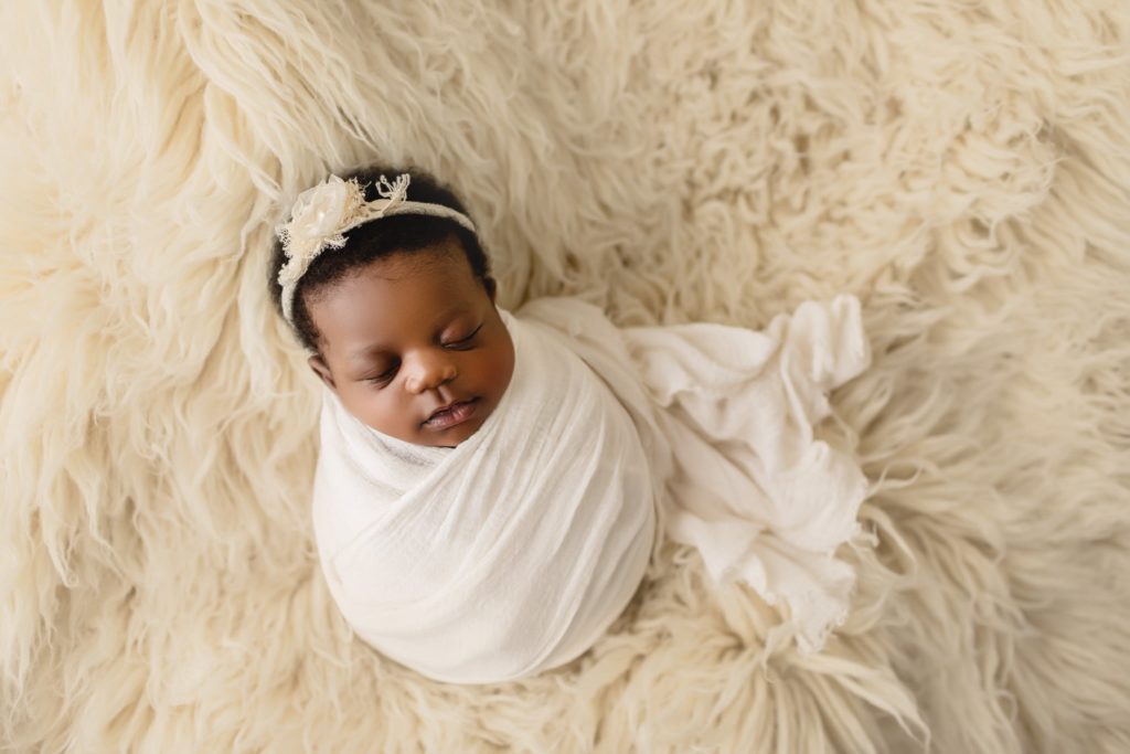 Newborn baby girl in studio photo shoot with subtle feminine touches.