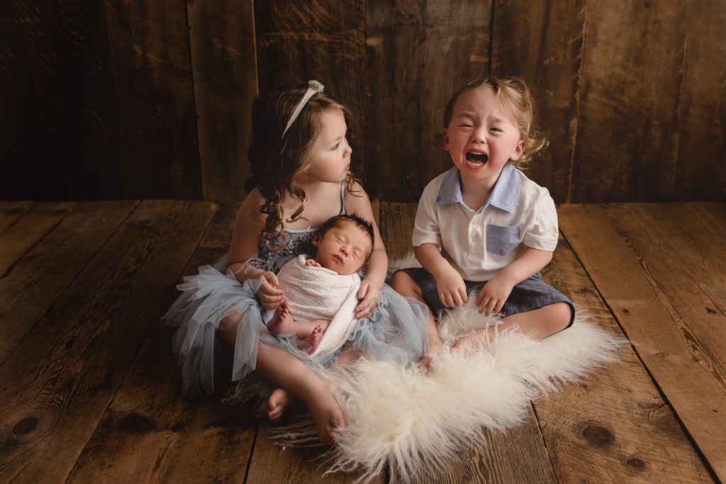 Newborn photoshoot in studio with siblings and mom and dad.