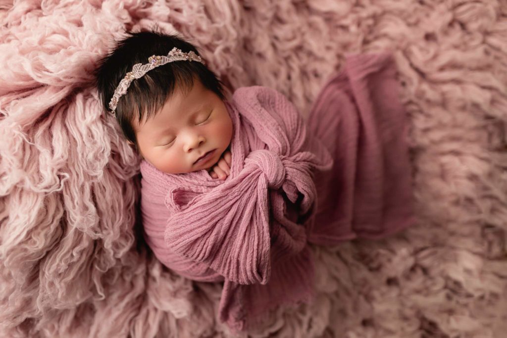 Newborn baby girl in studio photo shoot using pinks and textured backdrops.