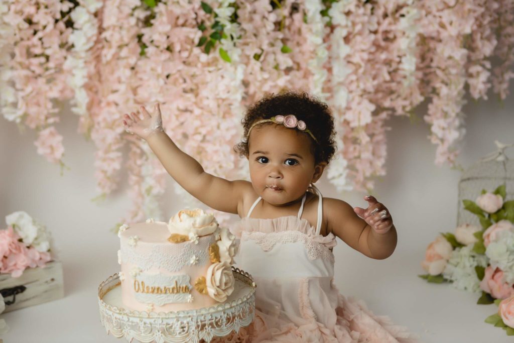 Floral milestone cake smash photoshoot with baby girl eating cake